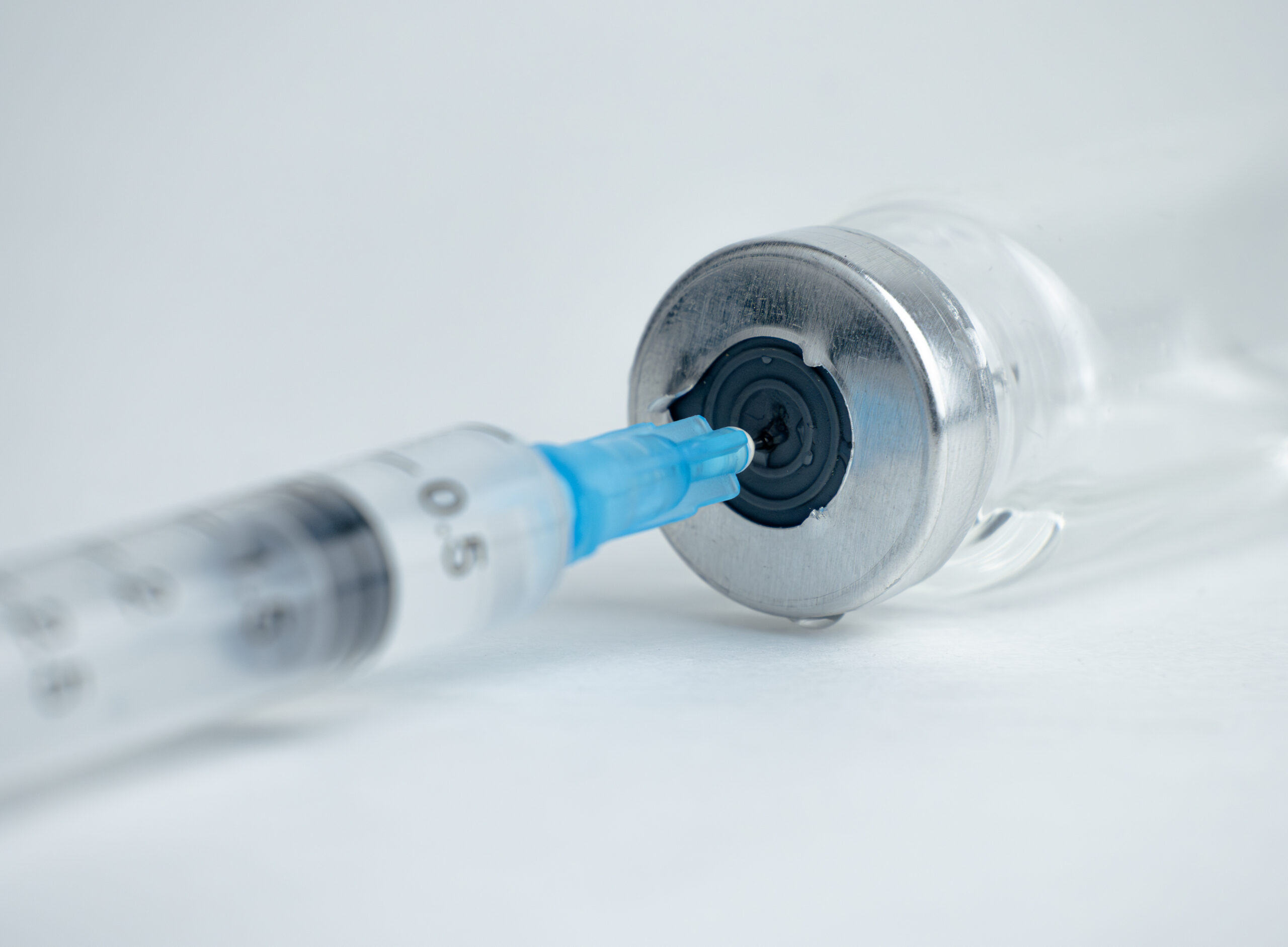 A syringe is inserted into a vial