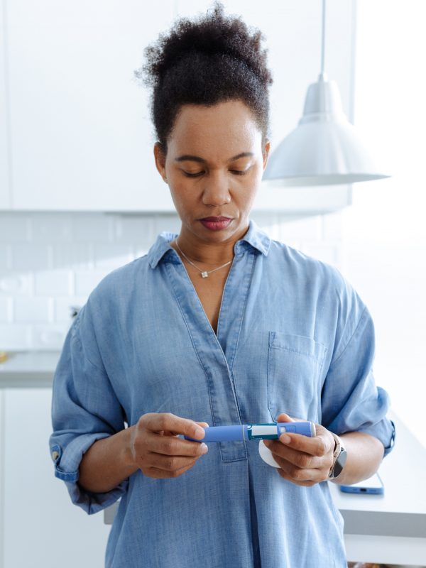 A woman administers an insulin injection in a bright and contemporary kitchen setting, emphasizing health awareness.